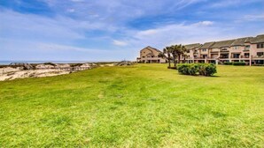 Un hôtel doté d’une grande pelouse, offrant une vue sur la plage et comprenant un bâtiment avec de nombreux balcons.