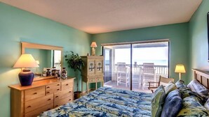 Een slaapkamer met een bed, een dressoir en een balkon met uitzicht.