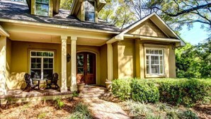A two-story house with a covered porch, a front door, and a window. - 14-sweetwater-oaks-drive (Fernandina Beach)