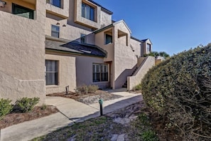 A multi-story building with a stucco exterior, a covered patio, and a well-maintained garden area. - 608-sailmaker (Fernandina Beach)