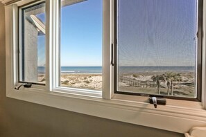 A room with a view of a beach, including a sandy area and a wooden pier. - 608-sailmaker (Fernandina Beach)