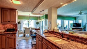 A spacious kitchen with granite countertops, wooden cabinets, and a large island with a sink.