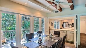 A spacious kitchen with modern appliances, a dining area with a glass table, and a ceiling fan. - 17-beach-walker-road (Fernandina Beach)