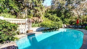 A swimming pool surrounded by lush greenery and a stone patio. - 17-beach-walker-road (Fernandina Beach)