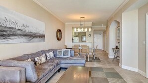 A spacious living area with a sectional sofa, a coffee table, and a dining area with chairs and a table. - 88-ocean-place (Fernandina Beach)