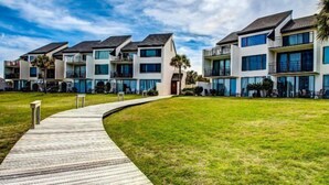 A modern multi-story residential building with a wooden walkway leading to the entrance. - 1196-beach-walker (Fernandina Beach)