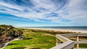 A beach view with a wooden deck, grassy area, and ocean. - 1135-beach-walker (Fernandina Beach)