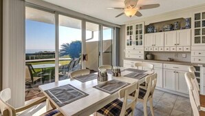 Comedor con una mesa dispuesta para cuatro personas, ventilador de techo y vistas al exterior a través de puertas correderas de vidrio.