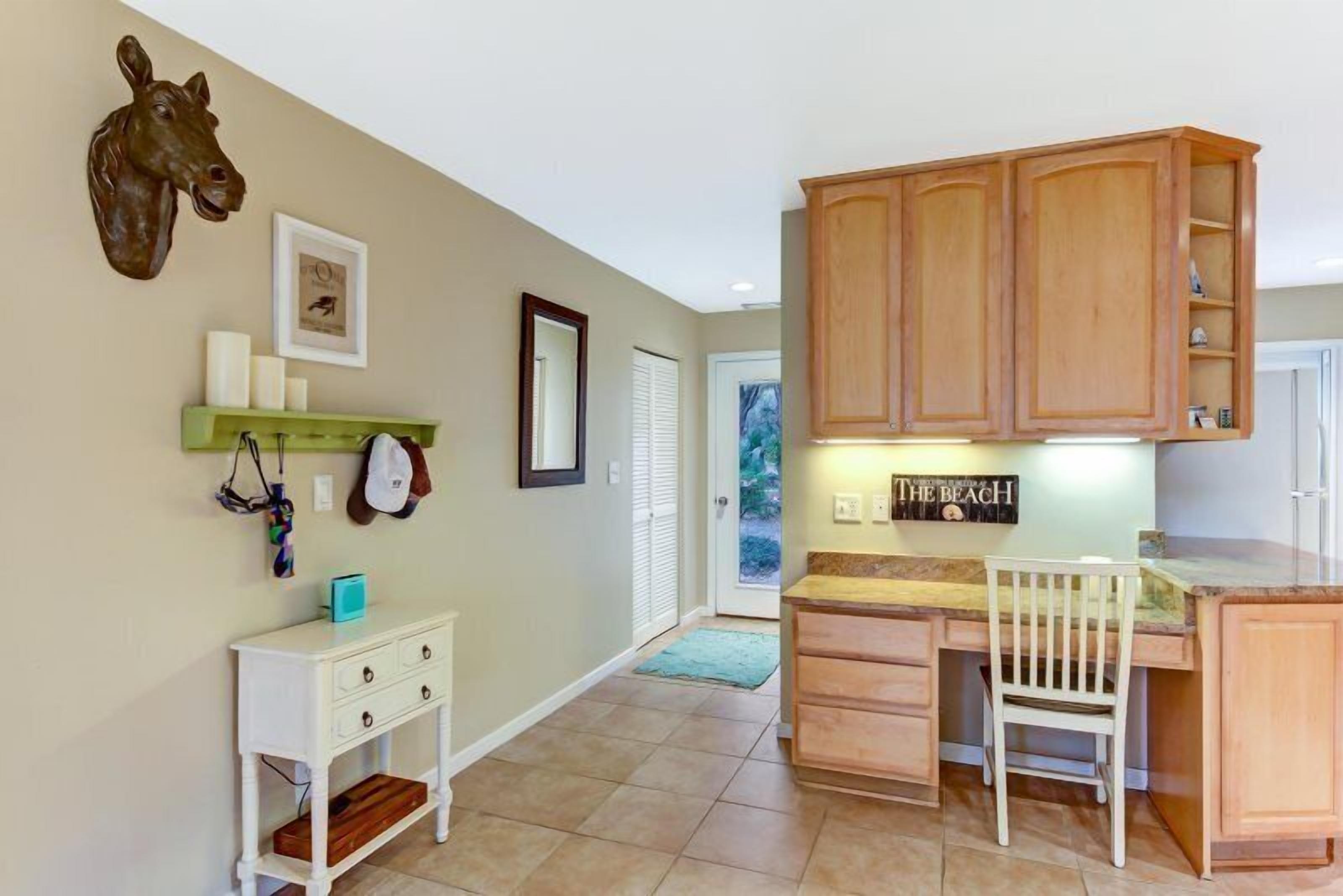 A kitchen with wooden cabinets, a white chair, a small white table, and a mounted horse head sculpture.