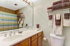 A bathroom with a white sink, two faucets, a mirror, and a striped shower curtain.