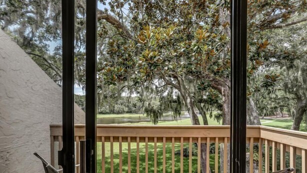 A balcony with a view of a golf course and trees. - 2100-beachwood (Fernandina Beach)
