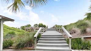 A wooden staircase leading to a covered area with a view of the beach and dunes. - 1129 Beach Walker (Fernandina Beach)