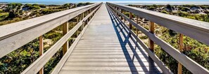 A wooden boardwalk leading to a beach with a clear view of the ocean. - 306-sailmaker (Fernandina Beach)