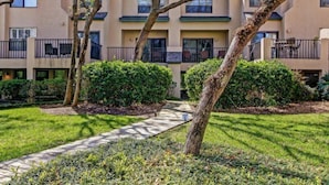 A multi-story residential building with balconies, a paved walkway, and well-maintained landscaping. - 306-sailmaker (Fernandina Beach)