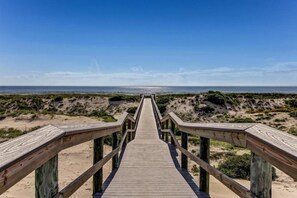 A wooden boardwalk leading to a beach with dunes and a clear sky. - 306-sailmaker (Fernandina Beach)