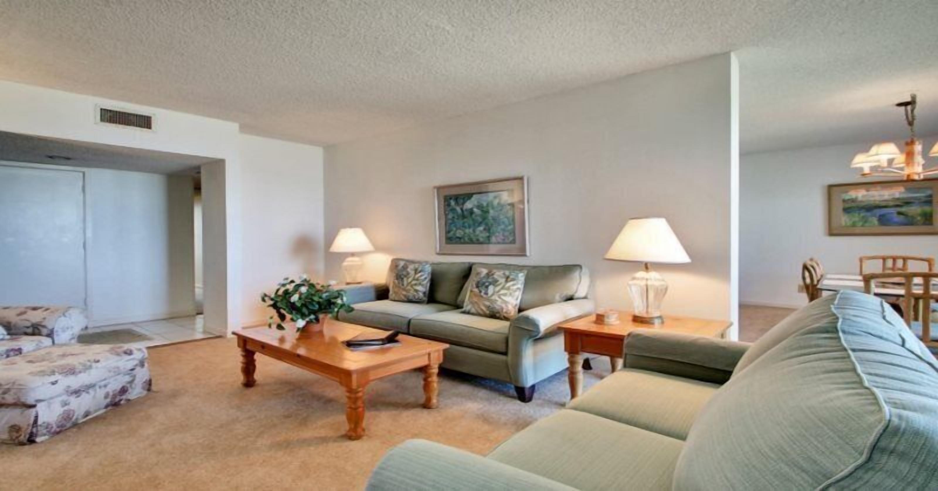 A living room with a sofa, two side tables, a coffee table, and a painting on the wall.