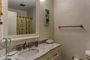 A bathroom with a marble sink, a mirror, a towel rack, and a framed artwork on the wall.