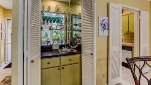 A kitchen with a glass display cabinet, a sink, and a chair.