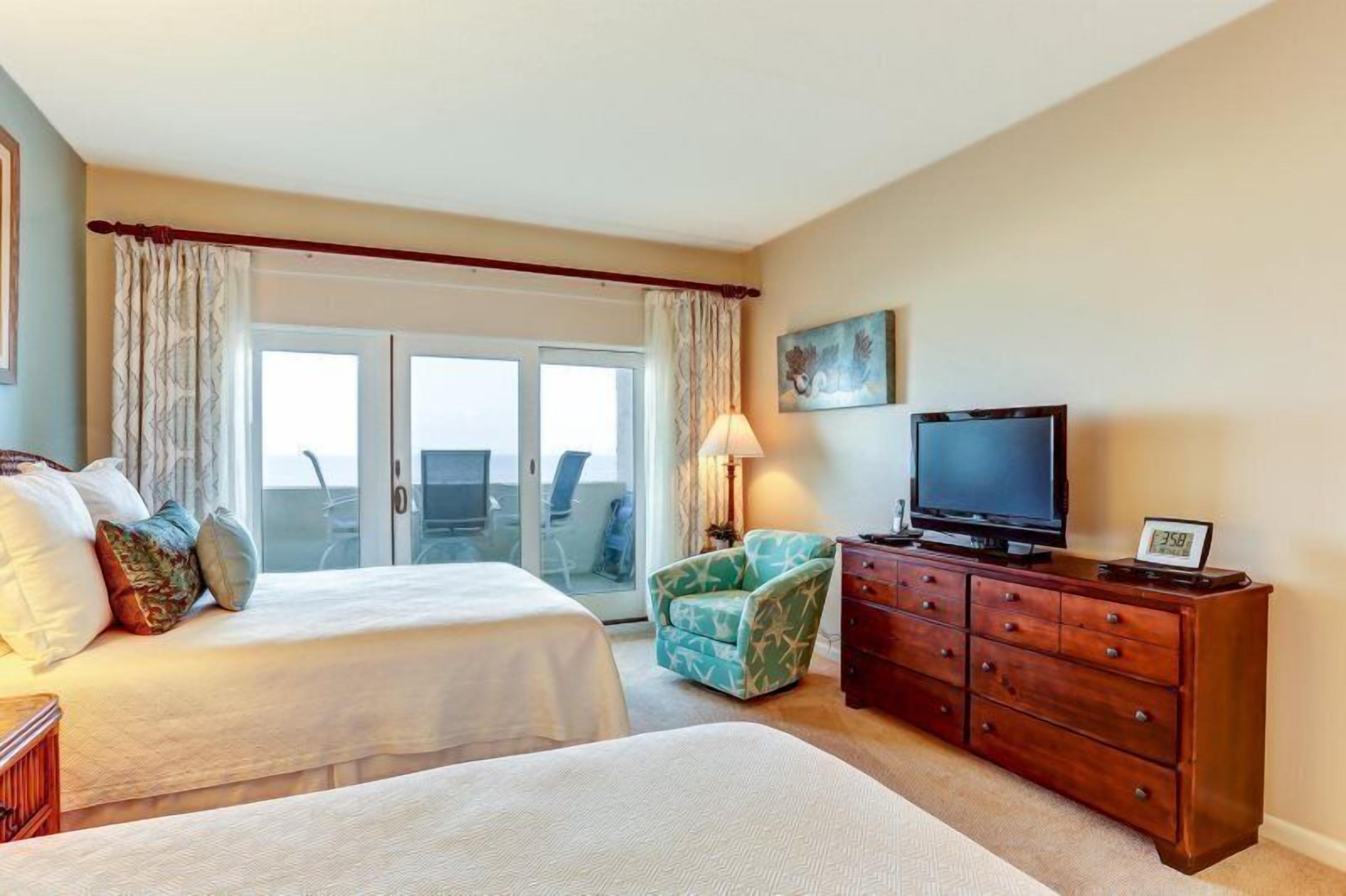 A hotel room with a bed, a TV, a dresser, and a chair.