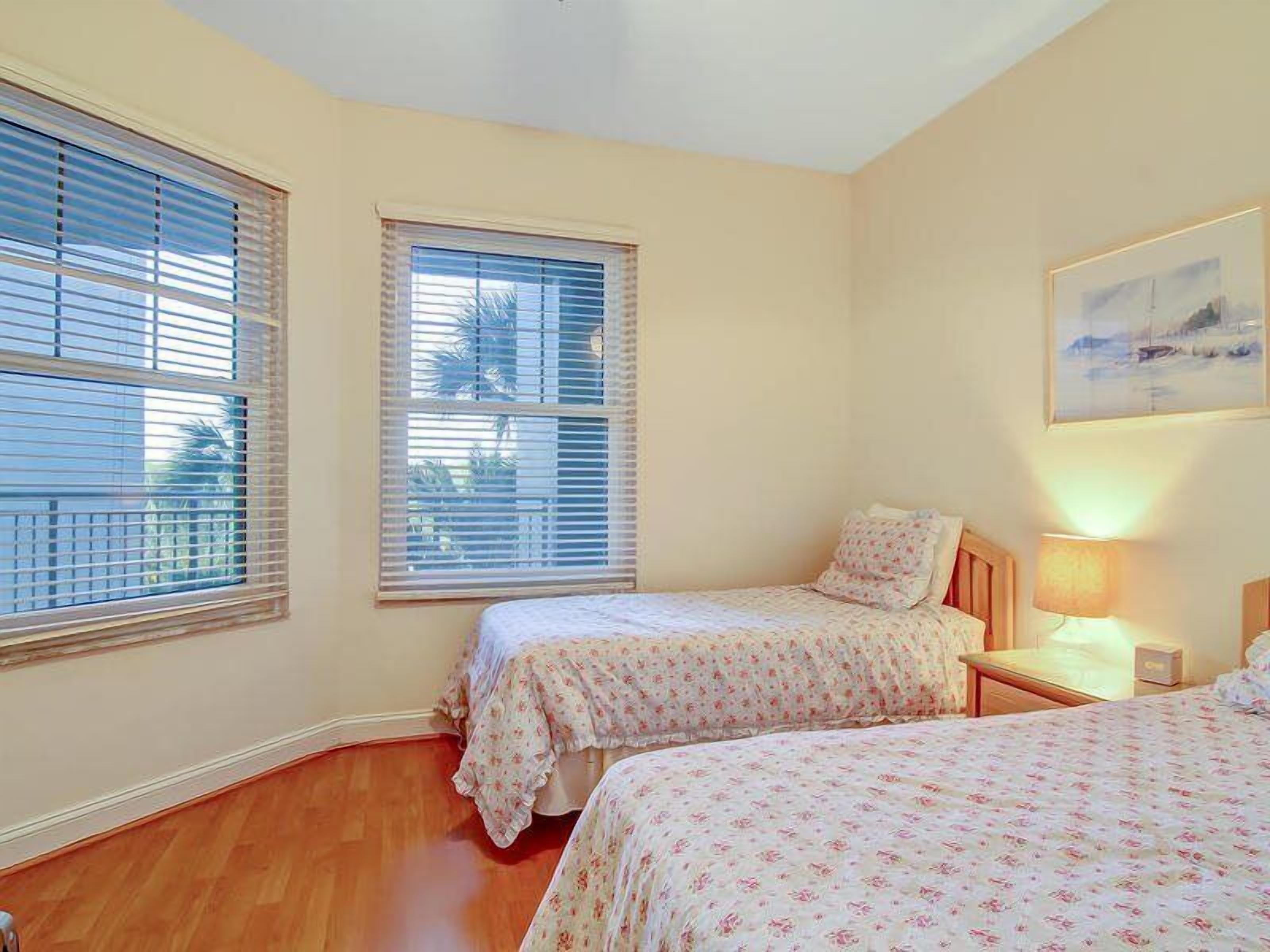 A bedroom with two beds, a nightstand, a lamp, and a painting on the wall.