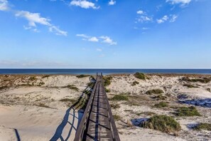 A wooden boardwalk leading to a beach with sand dunes and sparse vegetation. - 203-sailmaker (Fernandina Beach)
