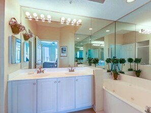 Une salle de bain avec un meuble-lavabo à deux vasques, un grand miroir et une baignoire.