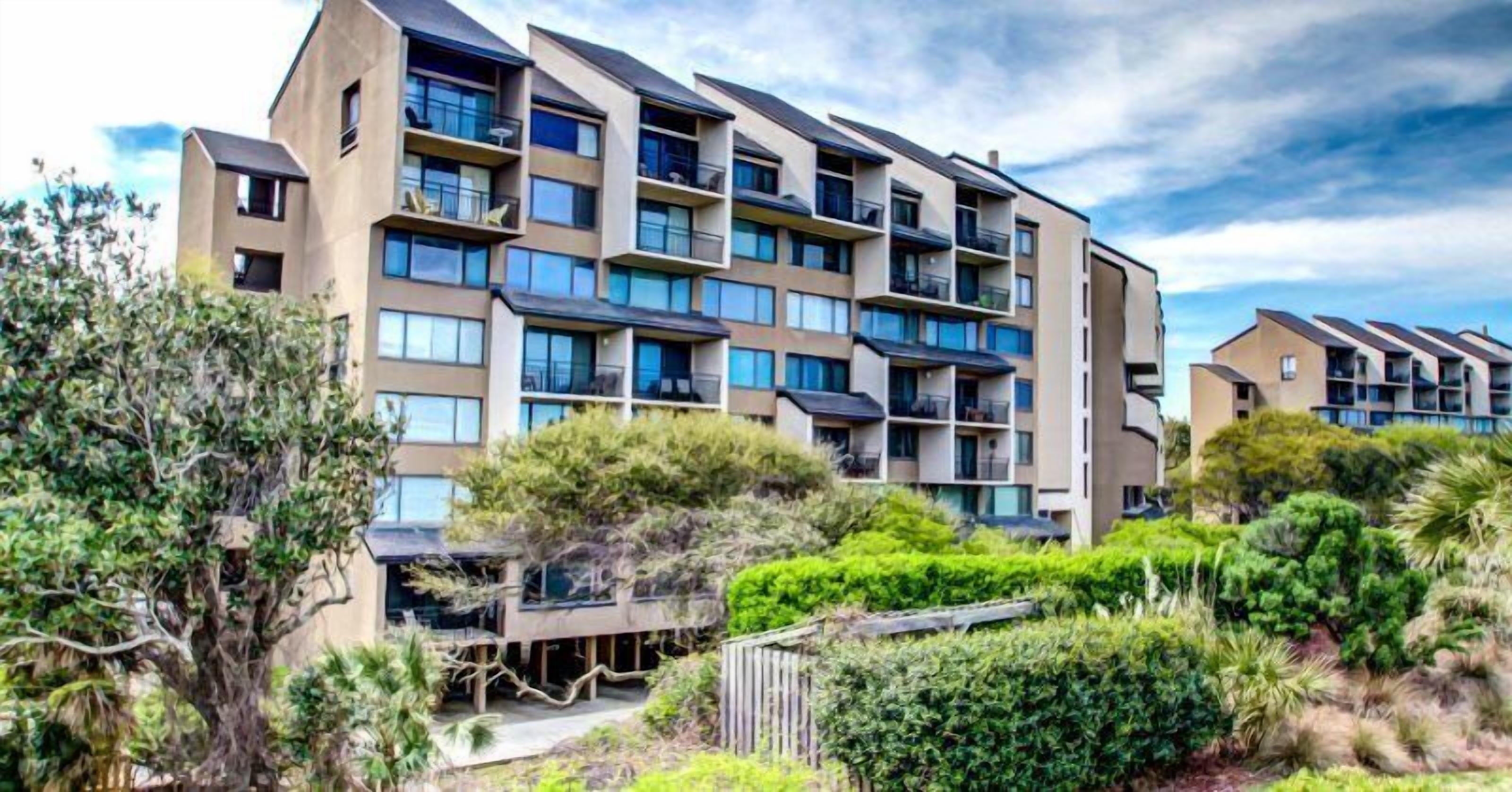 A multi-story residential building with balconies, surrounded by lush greenery.