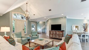 A spacious living room with a large sofa set, a coffee table, and a TV on a wooden cabinet. - 13-green-winged-teal (Fernandina Beach)