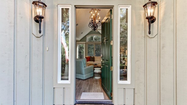 A hallway with a green door, a light-colored wall, and a chandelier. - 13-green-winged-teal (Fernandina Beach)