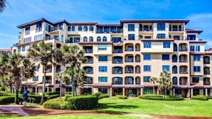 Un hôtel à plusieurs étages doté de balcons, d’une pelouse bien entretenue et de palmiers.