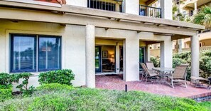 A hotel exterior with a covered patio area, outdoor seating, and a view of the surrounding greenery. - 1801-turtle-dunes (Fernandina Beach)