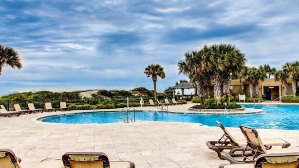 A pool area with lounge chairs and palm trees.