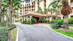 A hotel with a central courtyard, palm trees, and a covered entrance.