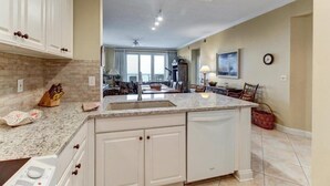 A kitchen with white cabinets, a granite countertop, and a built-in dishwasher. - 12-ocean-place (Fernandina Beach)