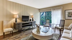 Una sala de estar moderna con un televisor de pantalla plana, una mesa de centro redonda y una zona de estar con sofá y sillones.