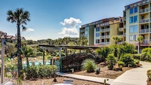 A hotel with multiple balconies, a pool, and a landscaped garden area. - 1354-shipwatch (Fernandina Beach)