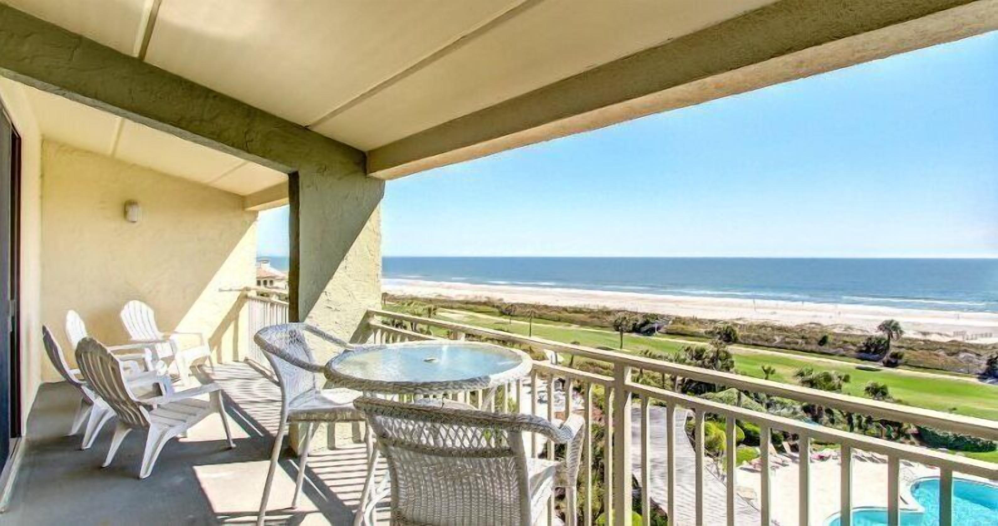 Een balkon met rieten meubilair en uitzicht op het strand.