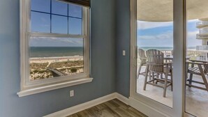 Ein Zimmer mit großem Fenster und Meerblick, inklusive Balkon mit Gartenmöbeln.