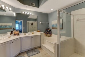 A bathroom with a large vanity, a glass shower enclosure, and a mirror with lights. - 60-ocean-place (Fernandina Beach)