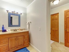 A bathroom with a wooden vanity, a blue-tiled sink, and a mirror with a blue border. - 2594 Forest Ridge Drive (Fernandina Beach)