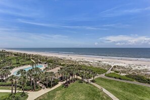 A resort with a pool, palm trees, and a beach. - 1869-turtle-dunes (Fernandina Beach)