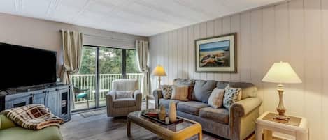 A living room with a television, sofa, armchair, and a coffee table.