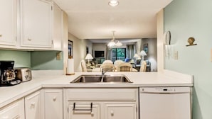 A kitchen with white cabinets, a built-in dishwasher, and a sink. - 2081-beachwood (Fernandina Beach)
