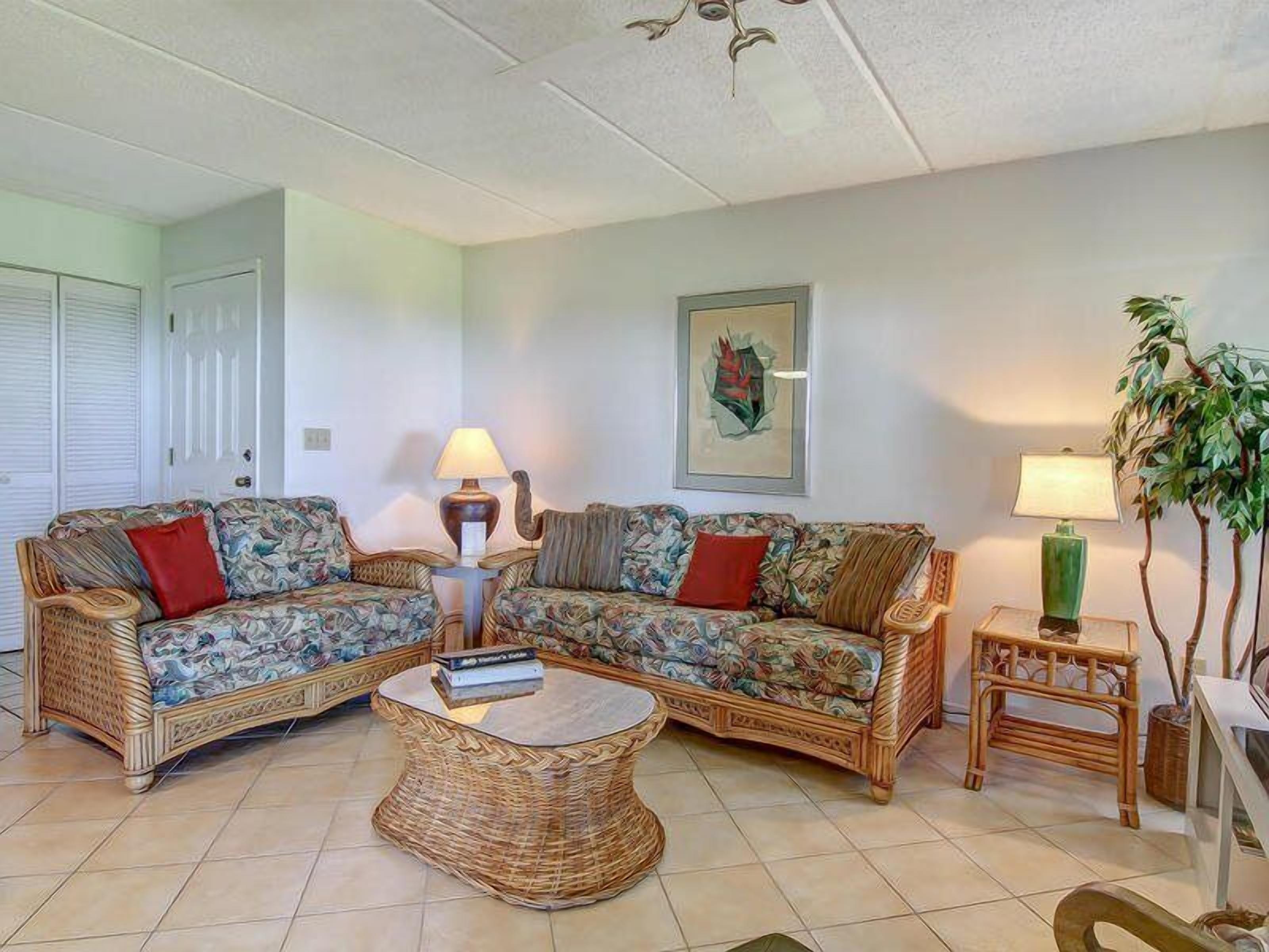 A living room with two wicker sofas, a round coffee table, and two side tables with lamps.