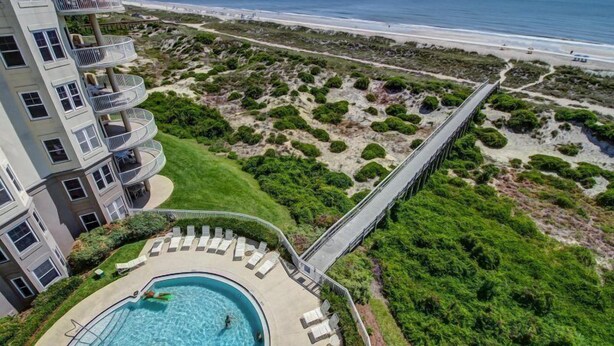 A hotel with a pool, a beach view, and a bridge connecting to the beach. - 61-ocean-place (Fernandina Beach)
