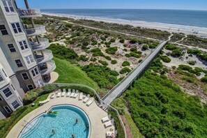 Un hotel con piscina, vista al mar y un puente que conecta con la playa.