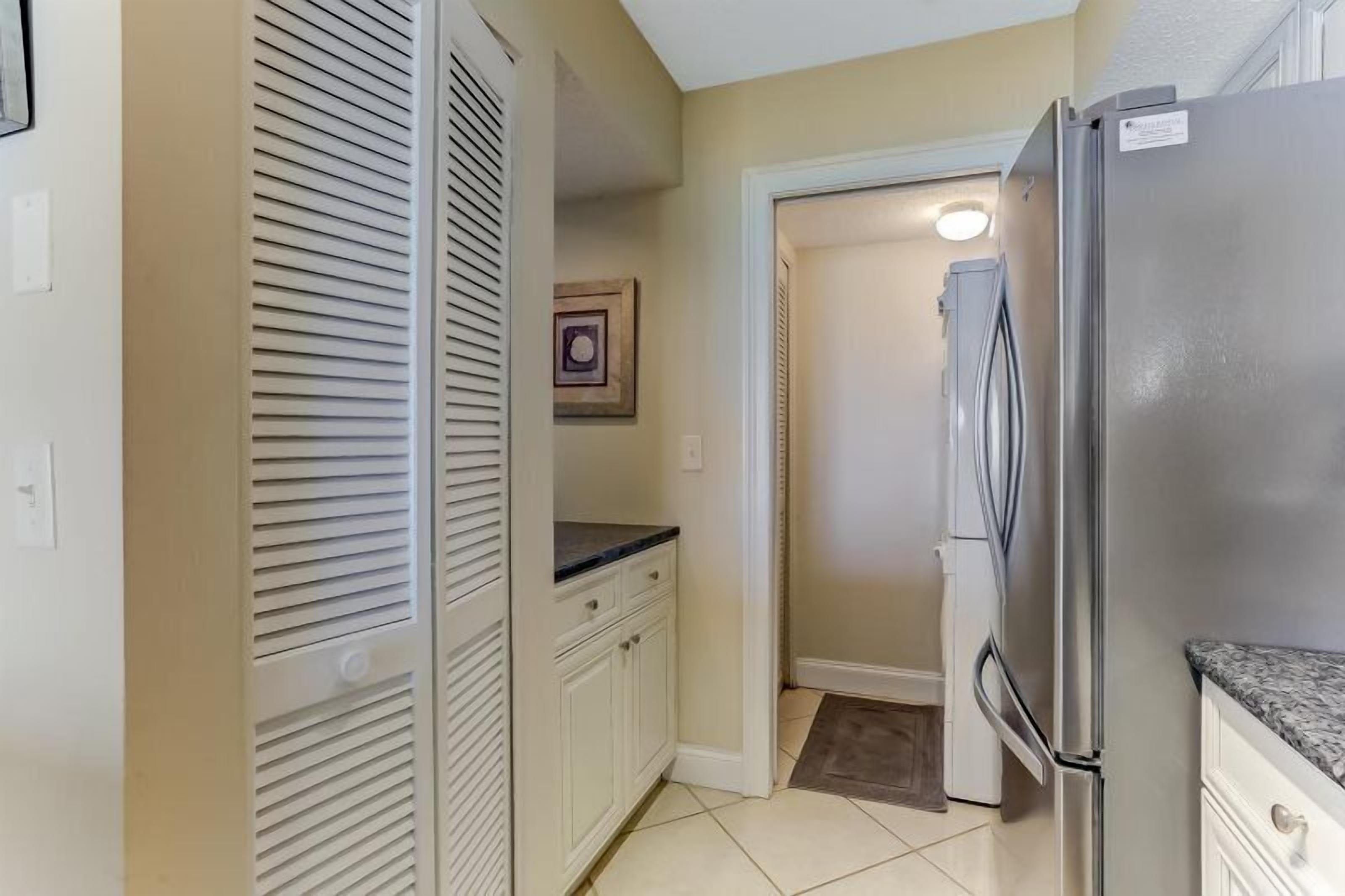 A compact kitchen with a stainless steel refrigerator, white cabinets, and a small countertop.