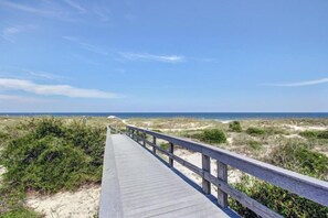 A wooden boardwalk leading to a beach with dunes and sparse vegetation. - B117-amelia-surf-and-racquet (Fernandina Beach)