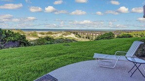 Een terras met uitzicht op het strand en een houten pier.