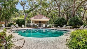 Une piscine avec des chaises longues et un kiosque.